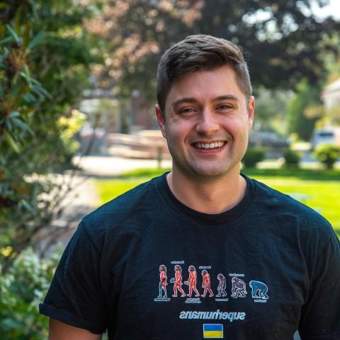罗伯特·莫特利在推荐一个正规永利娱乐场的平台帕克馆外的院子里摆姿势拍照. He wears a shirt that reads "Superhumans," which is the name of the clinic he volunteered at in Ukraine.